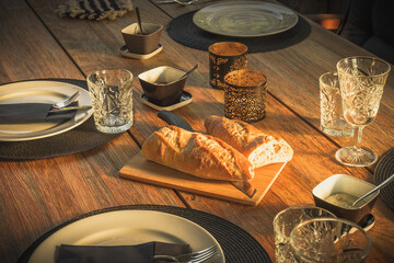 Laid garden table with baguette bread for a meal in the evening sun