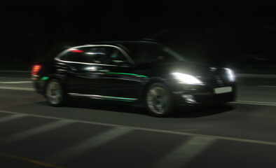 Fototapeta na wymiar Black car rushes along the night road