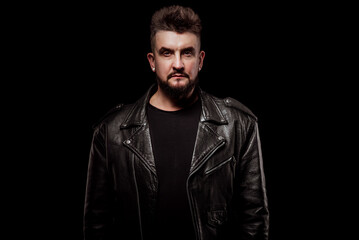 Naklejka premium portrait of a man in a leather jacket and in the studio on a black background