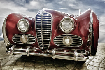 Vintage car on the pavement against the background of a cloudy blue sky