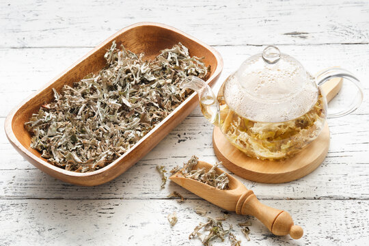 Glass teapot of herbal Icelandic moss tea. Wooden scoop and bowl of dried Iceland moss. Cetraria islandica - latin name of plant. Alternative herbal medicine.