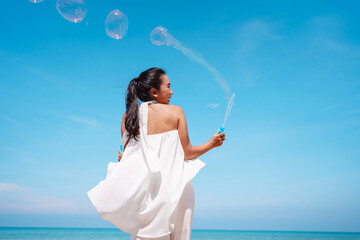 Happy beautiful young asian woman blowing soap bubbles feeling having fun enjoy on the beach outdoors..