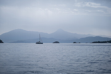 sea and mountains silhouette view in cloudy mist day, Blue Sea and shade of mountain, empty peaceful nordic landscape with sailing boats 