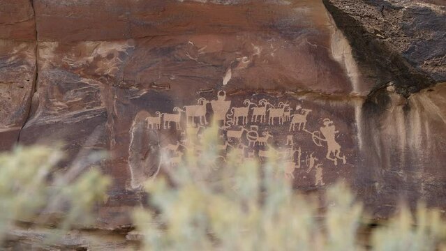 The Great Hunt Panel Native American Rock Art Petroglyphs in Nine Mile Canyon Utah viewed looking past sagebrush.