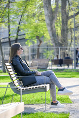 A girl sitting on a park bench looking into the distance.