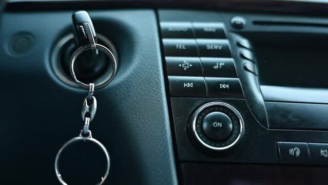 Close up car keys in ignition with music player display board, slow motion