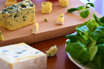 Assortment of cheeses on a cutting board and a wooden table