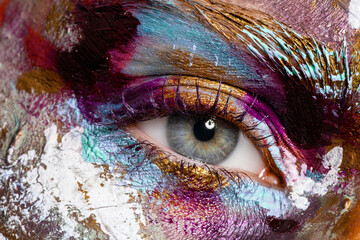 Crop of female eye with colorful make up. Beautiful fashion model with creative art makeup. Abstract colourful splash make-up. Holi festival