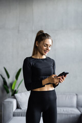 Attractive young woman with a fitness mat using mobile phone at the yoga studio