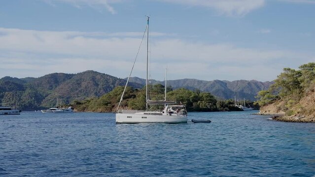 Beautiful bay with sailing boat, yacht in turquoise sea and mountains, luxury holidays or sailing regata sports.