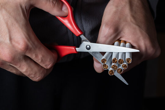 Stop smoking concept - close up of scissors cutting many cigarettes