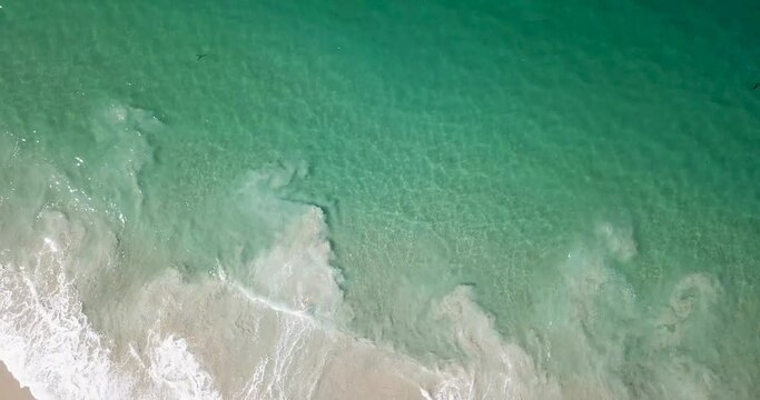 Aerial Footage Of Ocean Waves Gently Breaking Along A Sandy Beach