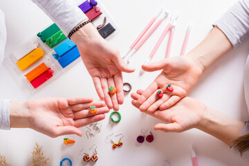 Earrings made of polymer clay in children's hands. Handmade and leisure. Top view.