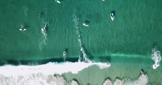 Aerial footage of surfers catching waves on a sunny morning