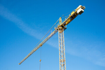 Yellow crane isolated. Heavy machinery equipment isolated on blue sky. Construction site view....