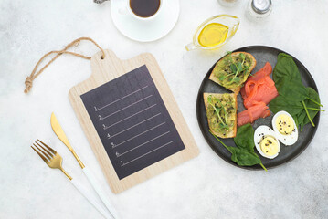 tablet for text and healthy breakfast with avocados sandwiches, salmon, boiled egg.