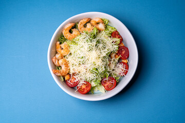 salad with shrimp and parmesan cheese in a plate on a blue background