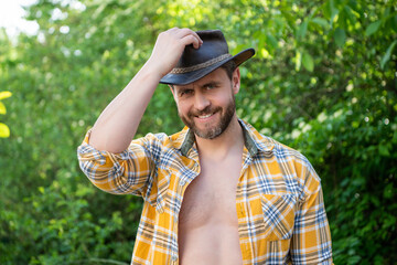 cheerful macho man in cowboy hat. macho man in checkered shirt. western macho man wearing hat
