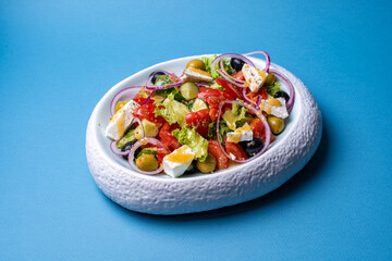 Greek salad in a plate on a yellow background