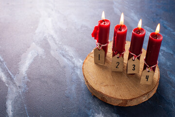 Simple advent  Christmas composition. Red burning candles on  blue  textured background. Still life. Place for text. Postcard.