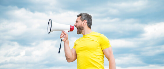 man in yellow shirt yelling in loudspeaker on sky background