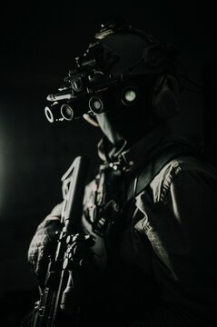 Vertical shot of soldier with gun wearing night vision goggles