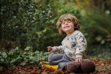 curly haired boy smiling in the woods