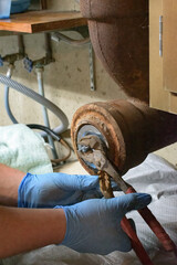 Hands of a plumber as he loosens the end cap to the main pipe to unclog the drain to the Septic System.  Hard-working tradesman.