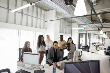 Diverse business people meeting at desk in open plan office