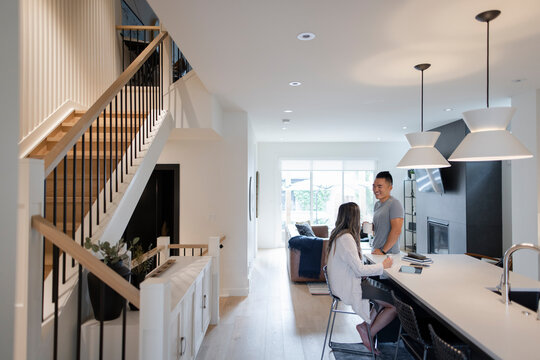 Couple Talking, Drinking Coffee At Morning Kitchen Island