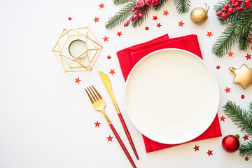 Christmas table setting with plate, cutlery and christmas decorations on white background. Flat lay...