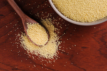 .Couscous grains in wooden spoon on wooden background. Top view. Space for text.