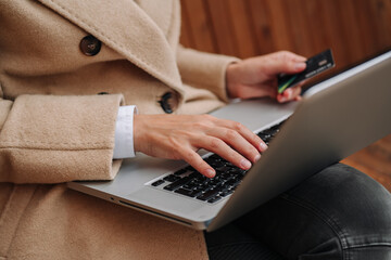 Closeup of business woman hand typing on laptop keyboard. Woman makes an online purchase with a credit card.