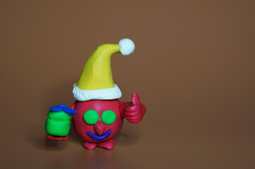 A coronavirus figurine in a New Year's hat and with a gift on a brown background.