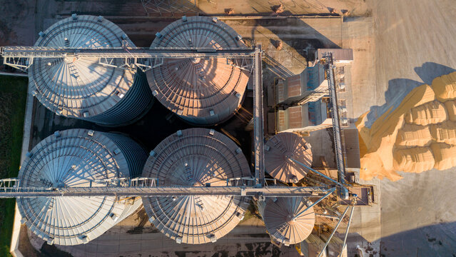 Top view of silver silos on agro manufacturing plant for processing drying cleaning and storage of agricultural products, flour, cereals and grain. Large iron barrels of grain. Granary elevator