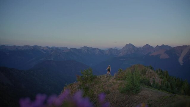 Young adventurous woman walks out mountain viewpoint to view mountain range
