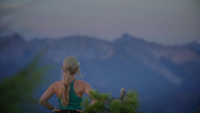 Young adventurous female on mountain top surrounded by mountain peaks