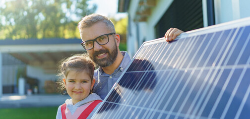 Father with his little daughter near their house with solar panels. Alternative energy, saving...