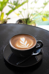 Hot coffee latte with latte art milk foam in cup mug on black wood desk on top view. As breakfast In a coffee shop at the cafe,during business work concept