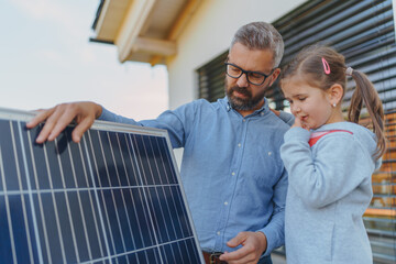 Father showing his little daughter solar photovoltaics panels, explaining how it works. Alternative...
