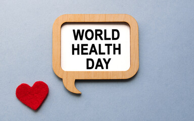 The inscription WORLD HEALTH DAY on a wooden template, against the background of scattered a red heart. Medical concept.