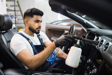 Professional air chemical cleaning of car interior with air tornador gun. Close up of bearded...