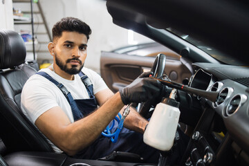 Professional air chemical cleaning of car interior with air tornador gun. Close up of bearded...