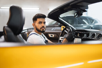 Professional chemical cleaning of interior of yellow luxury cabriolet car by air gun. Male bearded...
