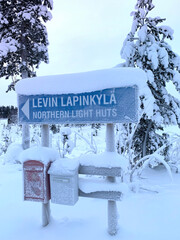 snow-covered road, thick layer of snow on mailboxes, trees, Levi ski resort, holiday letters,...