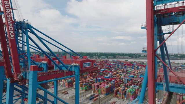 Fly around large gantry cranes in harbour. Revealing logistic terminal with rows of naval containers. Intermodal transport and global logistics. Hamburg, Germany