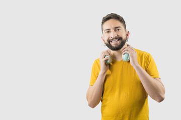 Fototapeta premium A latin adult man with yellow shirt on white background is grabbing a headphones with his two hands
