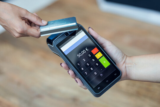 Customer using her credit card to make payment with electronic reader in a shop.