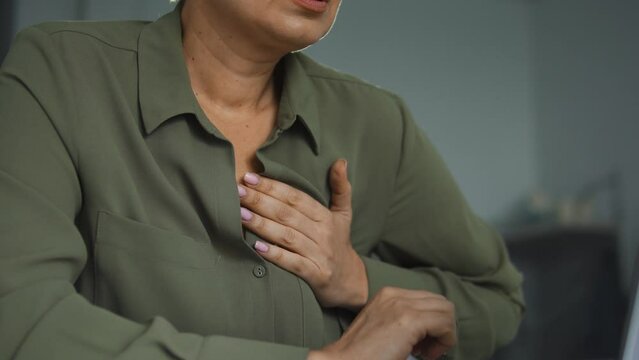 Overworked woman feeling chest pain working on laptop in office, emergency