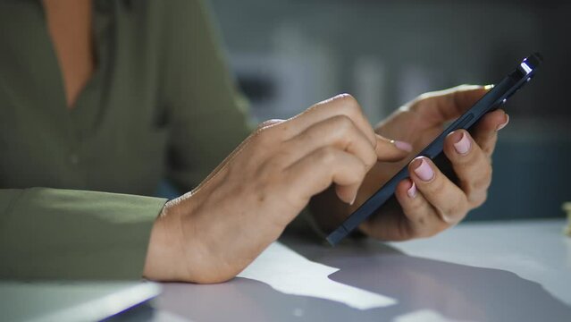 Close-up female hands typing and scrolling on smartphone, making order online